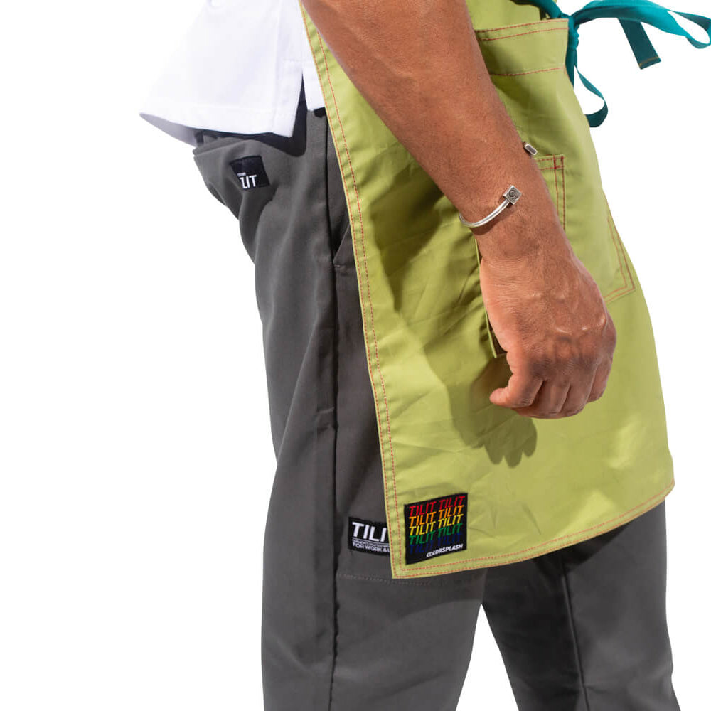 
                  
                    TILIT model wearing a green apron with teal accents straps
                  
                