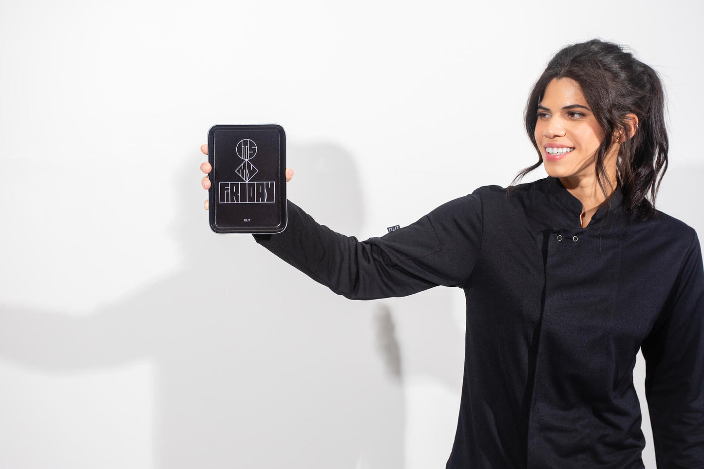 Woman holding a black rectangular cam tray with a design on a white background